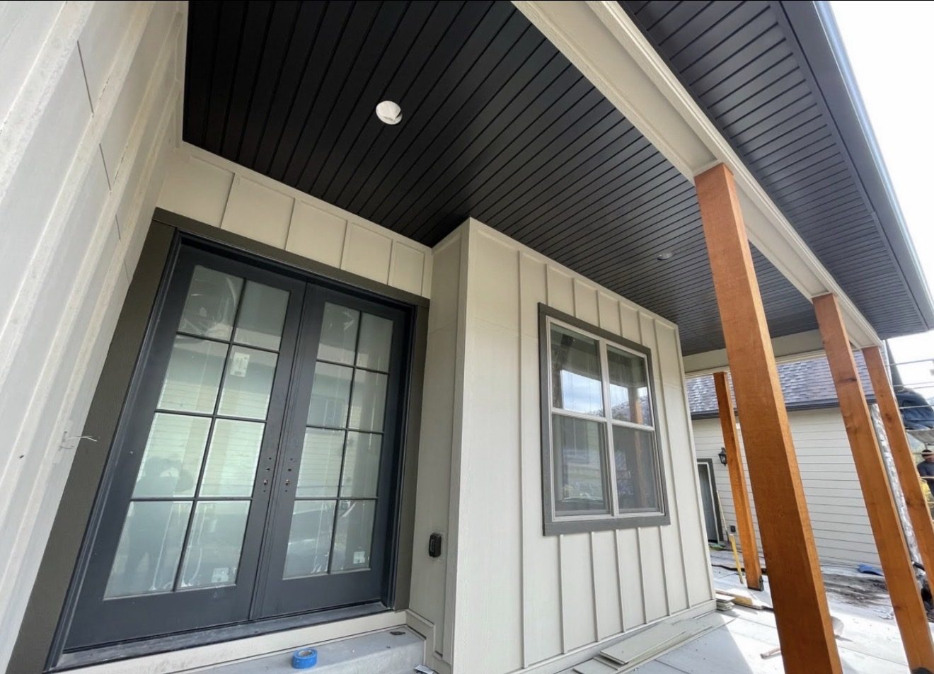 Front entry detail with dark stained wood porch ceiling and black doors