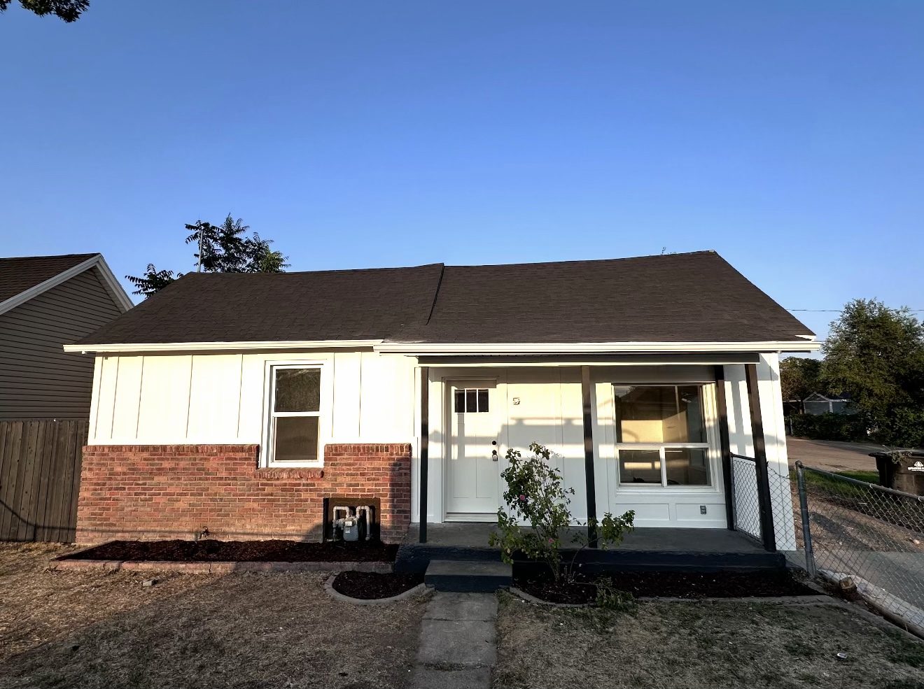 Home after, white Hardie board and batten siding with new soffit, fascia, and gutters