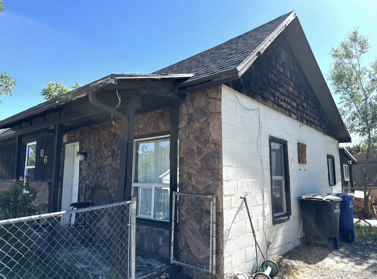Side of home before, exposed cinderblock and unpainted wood shake in the gable