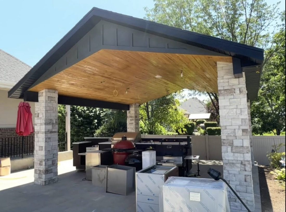 Pavilion after, finished stone columns, dark exterior, and wood plank ceiling