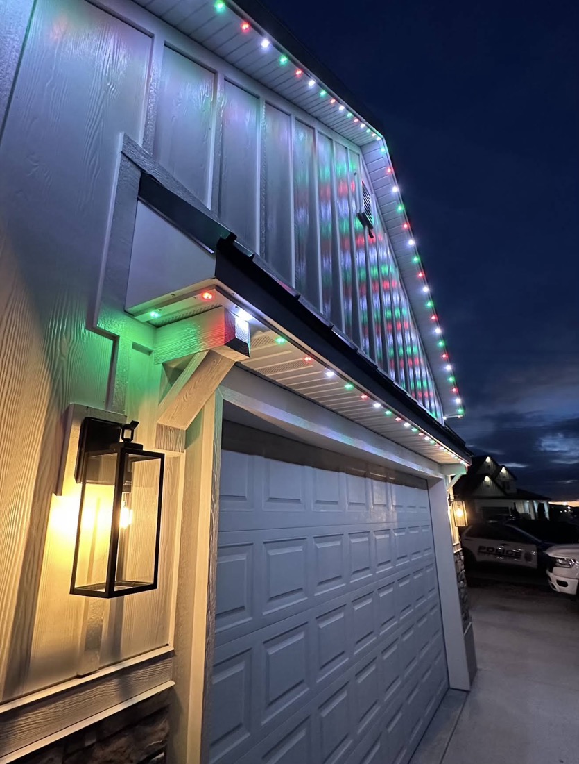 Home at night with permanent holiday lighting lit up red and green