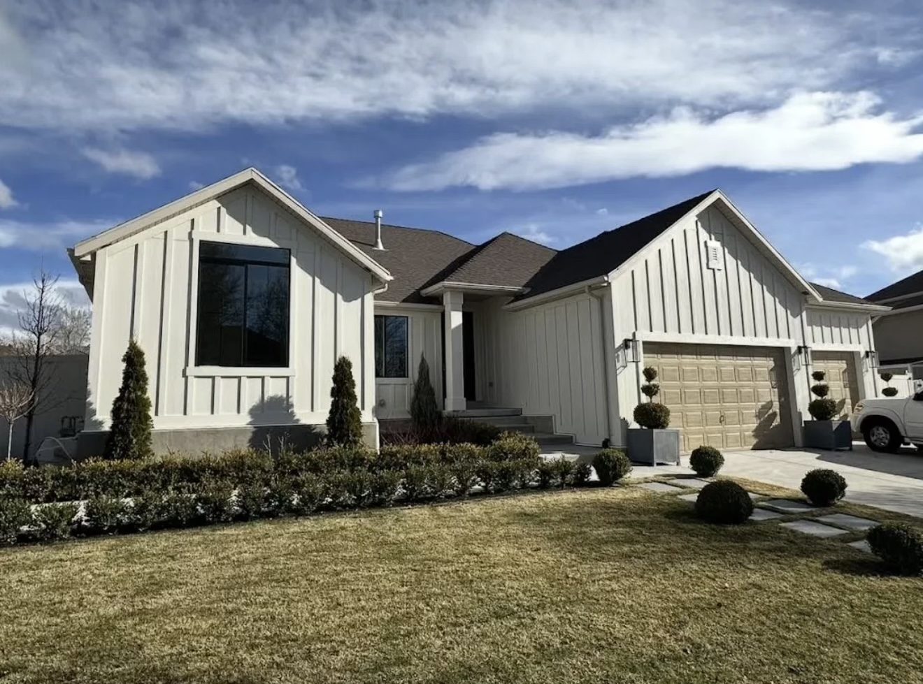 Home after, white Hardie board and batten siding with squared garage doors
