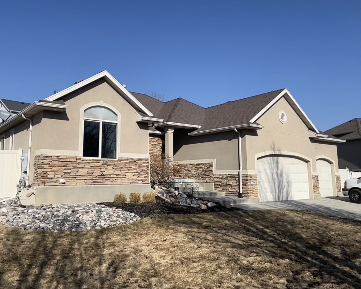 Home before, tan stucco exterior with stone accents